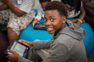 Student smiling while holding iPad