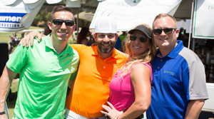 Three men and a woman smiling at Golfer's Dream Day event