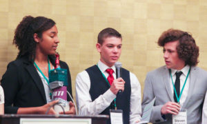 Teen students speaking into microphone