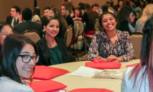 Group of teen female students sitting at table smiling