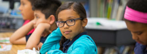 Young female student wearing glasses sitting at desk in classroom