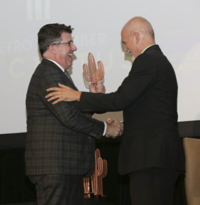 Two men shaking hands with one man receiving Copper Cactus Award