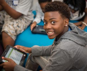 young African American boy smiling holding an iPad