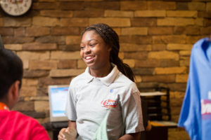 young African American girl smiling wearing Raising Cane's apron