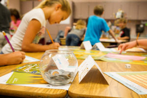 Children working on financial activity at desks in classroom