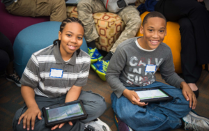 Two African American teen boys smiling holding iPads