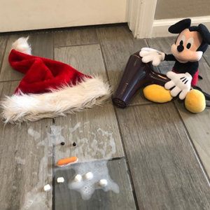 Mickey Mouse holding blow dryer next to melted snowman and Santa hat