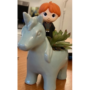 Toy figurine of red-headed boy riding in ceramic horse planter