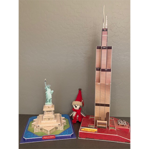 Stuffed owl sitting between figurines of Statue of Liberty and Empire State Building